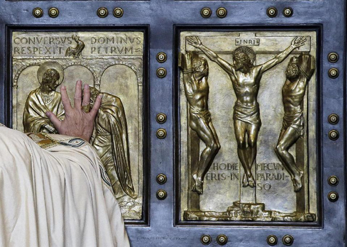 Pope Francis pushes open the Holy Door of St. Peter's Basilica, formally launching the Holy Year of Mercy, at the Vatican, Tuesday, Dec. 8, 2015. The 12-month jubilee emphasizes what has become the leitmotif of his papacy: to show the merciful and welcoming side of a Catholic Church more often known for its moralizing and judgment. (AP Photo/Gregorio Borgia)